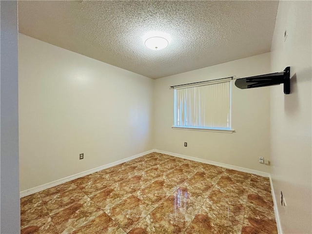 empty room with a textured ceiling and baseboards