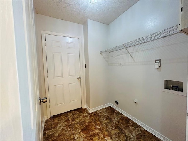 clothes washing area with baseboards, a textured ceiling, hookup for a washing machine, and laundry area