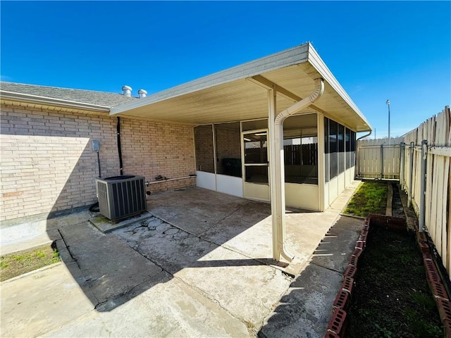 view of patio featuring a carport, cooling unit, a fenced backyard, and a sunroom