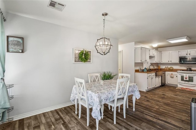 dining room featuring a notable chandelier, visible vents, baseboards, and dark wood-style flooring