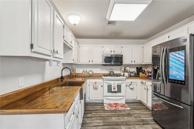 kitchen featuring visible vents, dark wood finished floors, appliances with stainless steel finishes, white cabinets, and a sink