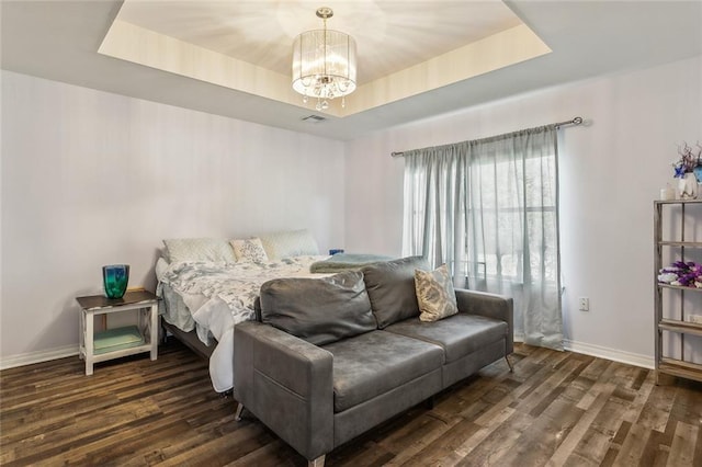 bedroom with baseboards, a raised ceiling, an inviting chandelier, and wood finished floors