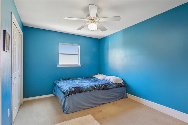 bedroom with a closet, baseboards, carpet, and a ceiling fan