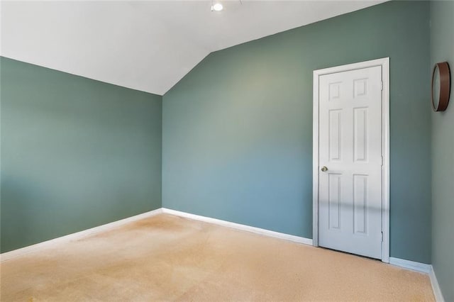 carpeted empty room with baseboards and vaulted ceiling