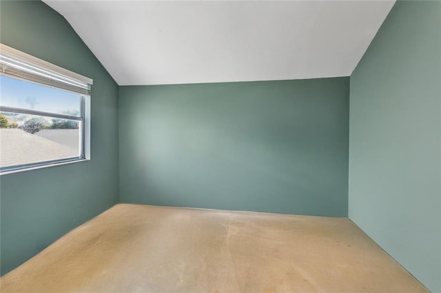 carpeted empty room featuring lofted ceiling