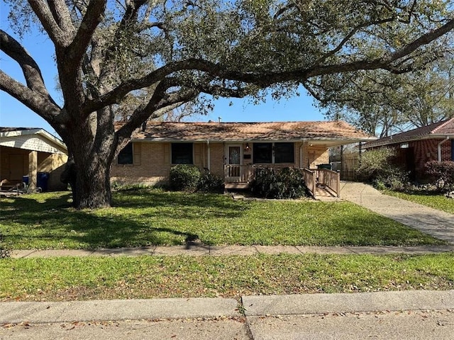 single story home with brick siding, covered porch, driveway, and a front lawn