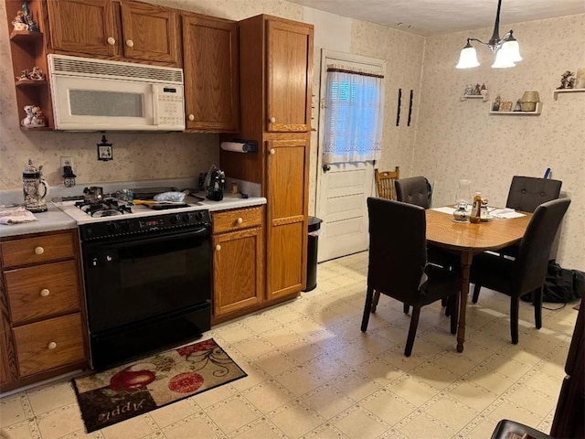 kitchen with light floors, white microwave, black range with gas cooktop, and wallpapered walls