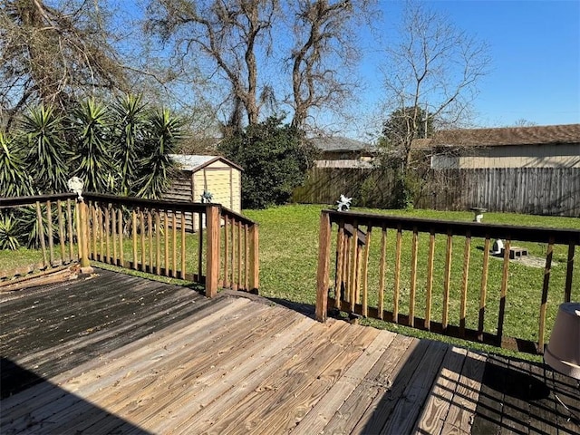 wooden deck with an outbuilding, a lawn, a fenced backyard, and a shed