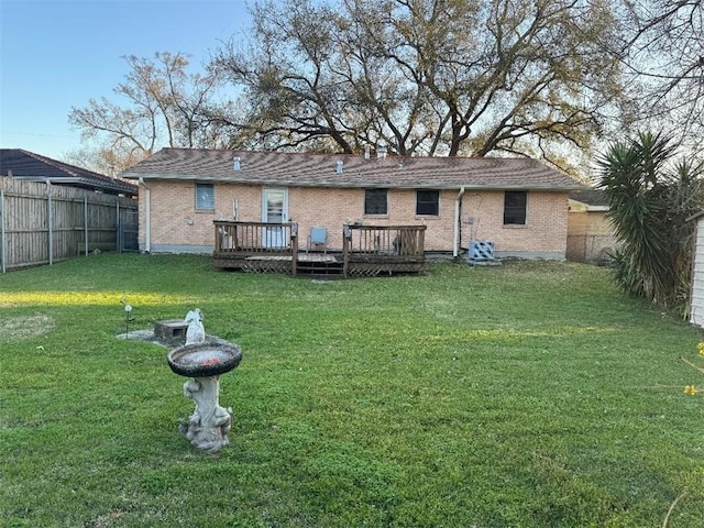 rear view of property with a wooden deck, brick siding, a fenced backyard, and a lawn