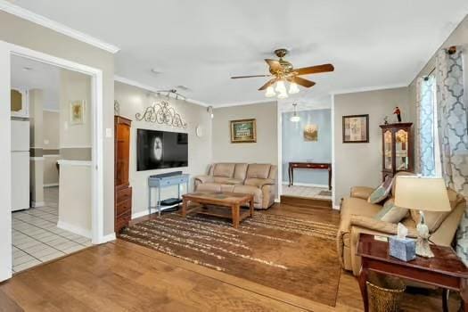 living area with a ceiling fan, wood finished floors, and ornamental molding