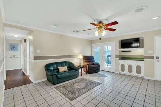 living room featuring ceiling fan, baseboards, ornamental molding, and tile patterned flooring