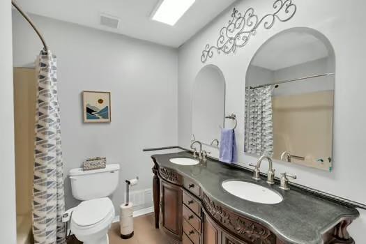 bathroom featuring double vanity, toilet, visible vents, and a sink