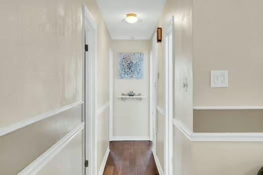 hallway with dark wood-type flooring and baseboards