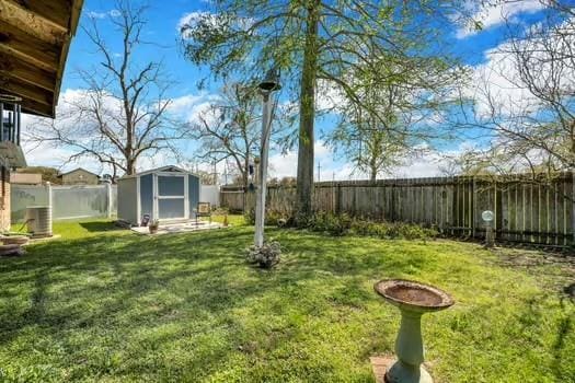 view of yard with an outbuilding, a fenced backyard, and a shed