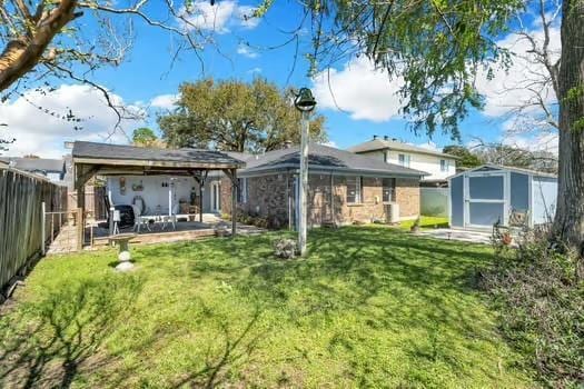 back of house with a fenced backyard, a shed, a gazebo, a yard, and an outdoor structure