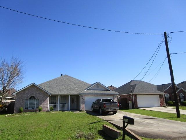 ranch-style home featuring brick siding, an attached garage, concrete driveway, and a front lawn