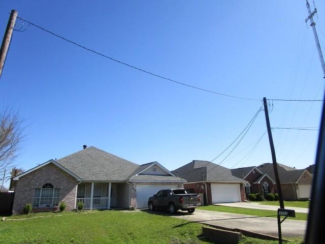 ranch-style home with a garage, brick siding, concrete driveway, and a front yard