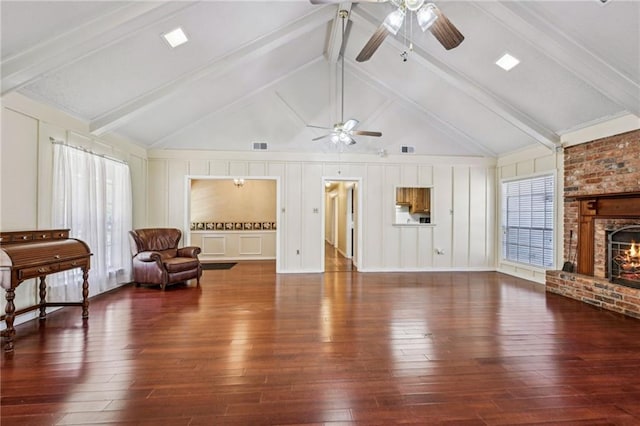 living room featuring beam ceiling, a decorative wall, a brick fireplace, and wood-type flooring