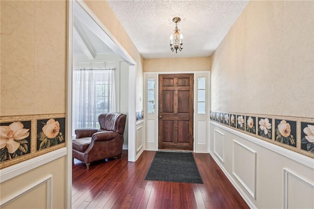 foyer entrance featuring a wealth of natural light, a textured ceiling, and dark wood-type flooring