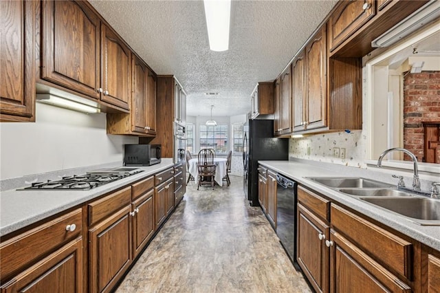 kitchen with black appliances, pendant lighting, a sink, a textured ceiling, and light countertops