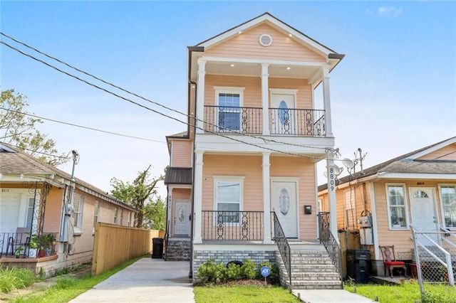 shotgun-style home featuring a porch, metal roof, and a balcony