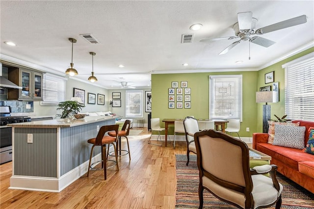 kitchen with a ceiling fan, ornamental molding, gas range, open floor plan, and a center island