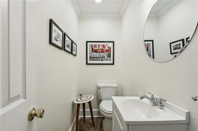 bathroom with crown molding, baseboards, toilet, a textured wall, and vanity