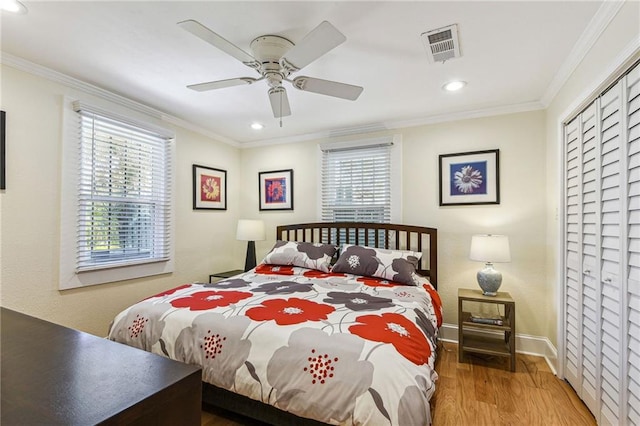 bedroom with baseboards, wood finished floors, visible vents, and ornamental molding