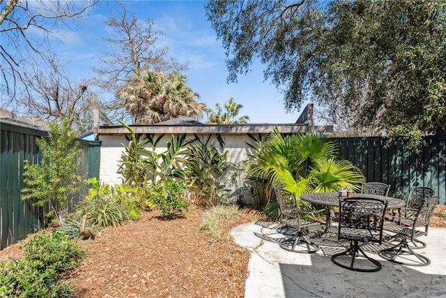 view of yard featuring a patio area, outdoor dining space, and fence