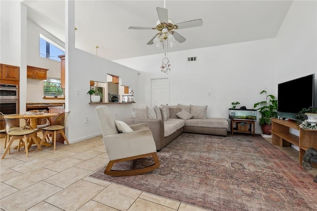 living room with a high ceiling, light tile patterned flooring, visible vents, and ceiling fan