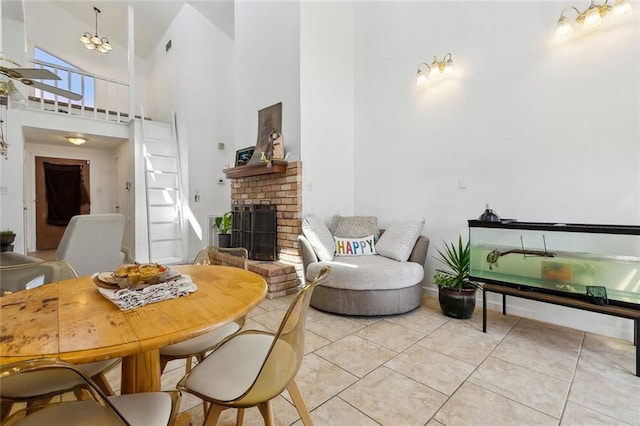 dining area with light tile patterned floors, baseboards, a high ceiling, and a brick fireplace