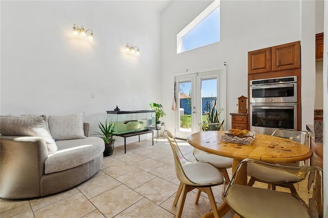 dining room with light tile patterned floors, a healthy amount of sunlight, french doors, and a high ceiling