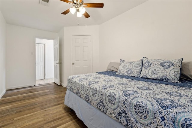 bedroom with a ceiling fan, visible vents, wood finished floors, and baseboards