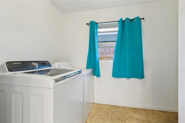 laundry room with laundry area, light tile patterned floors, baseboards, and washing machine and clothes dryer