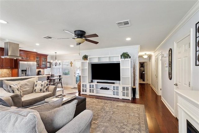 living room with visible vents, ceiling fan with notable chandelier, dark wood-style flooring, and crown molding