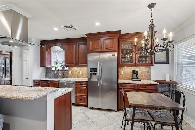 kitchen featuring visible vents, pendant lighting, a sink, stainless steel appliances, and glass insert cabinets