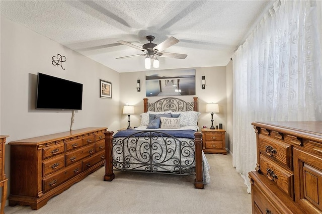 bedroom with light colored carpet, a textured ceiling, and a ceiling fan