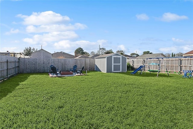 view of yard with a fire pit, a fenced backyard, a shed, and an outdoor structure