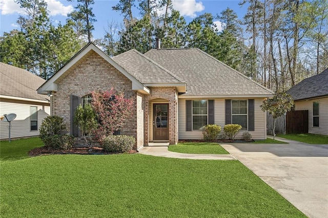 single story home with brick siding, a shingled roof, a front yard, and fence