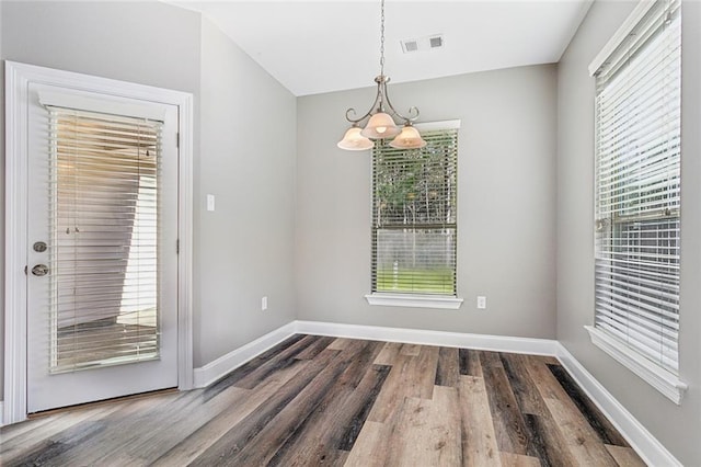 unfurnished dining area featuring plenty of natural light, wood finished floors, and visible vents