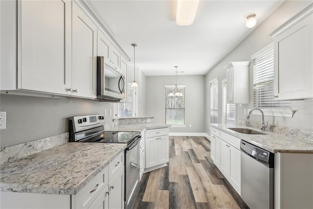 kitchen with wood finished floors, white cabinetry, stainless steel appliances, and a sink