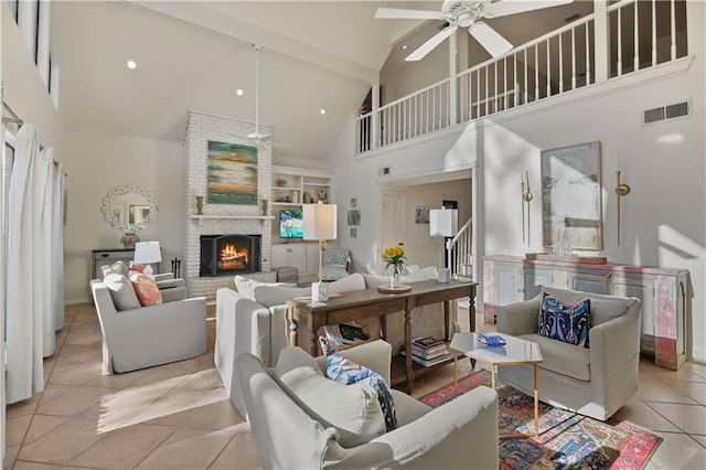 living area featuring tile patterned flooring, visible vents, a fireplace, high vaulted ceiling, and a ceiling fan