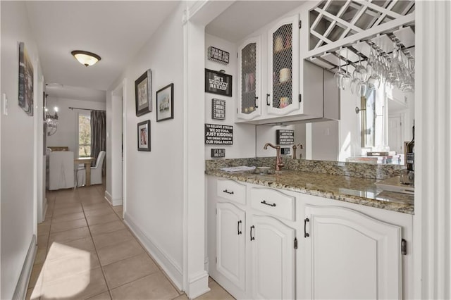 hall with light tile patterned floors, baseboards, and a sink