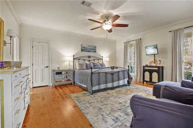 bedroom featuring ceiling fan, visible vents, light wood-style flooring, and ornamental molding