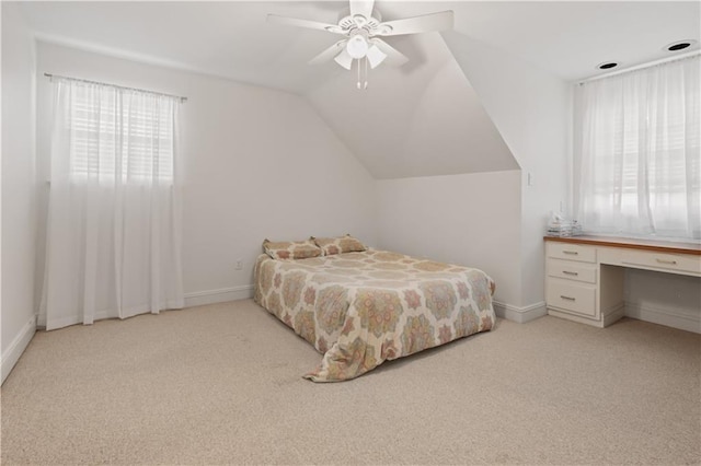 bedroom featuring built in desk, light colored carpet, baseboards, and lofted ceiling