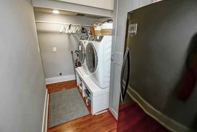 laundry area featuring laundry area, wood finished floors, baseboards, and washer and clothes dryer