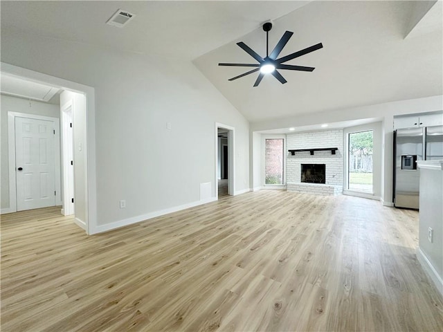 unfurnished living room featuring visible vents, attic access, a fireplace, ceiling fan, and light wood-style floors