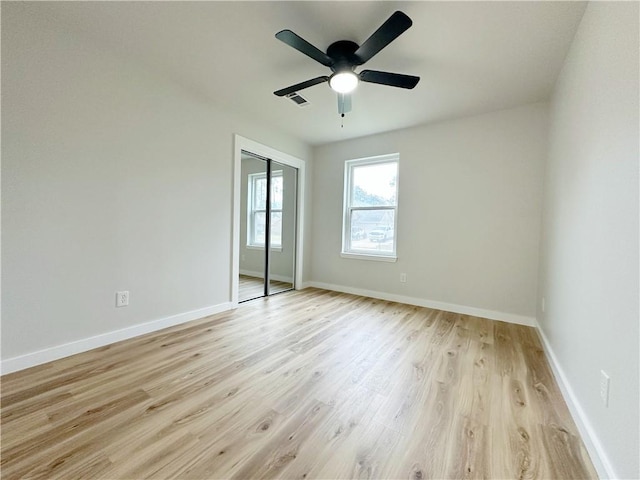 unfurnished bedroom with light wood-type flooring, baseboards, a closet, and visible vents