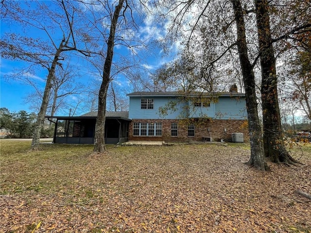 rear view of property featuring a yard, brick siding, central AC unit, and a sunroom