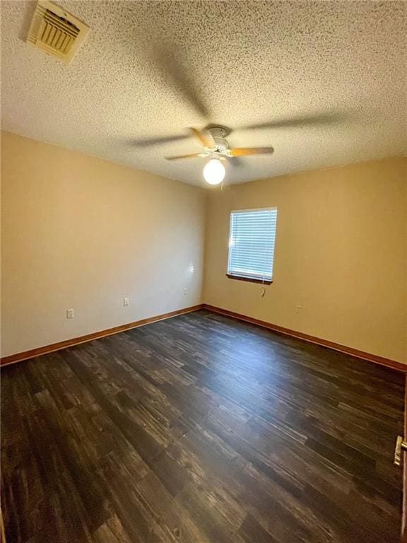 empty room with visible vents, baseboards, dark wood-style floors, and a ceiling fan